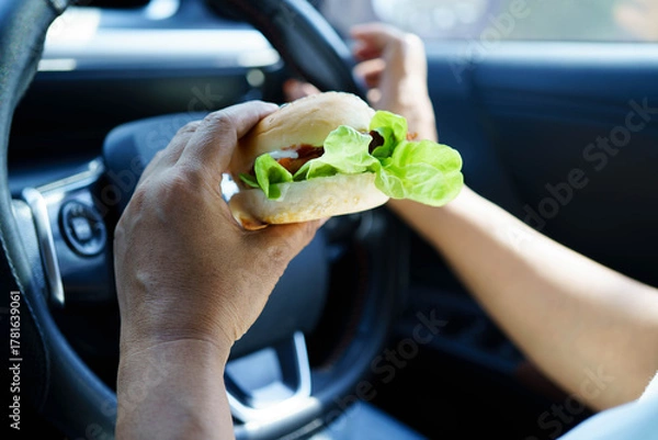 Fototapeta Asian woman driver hold and eat hamburger food in car.