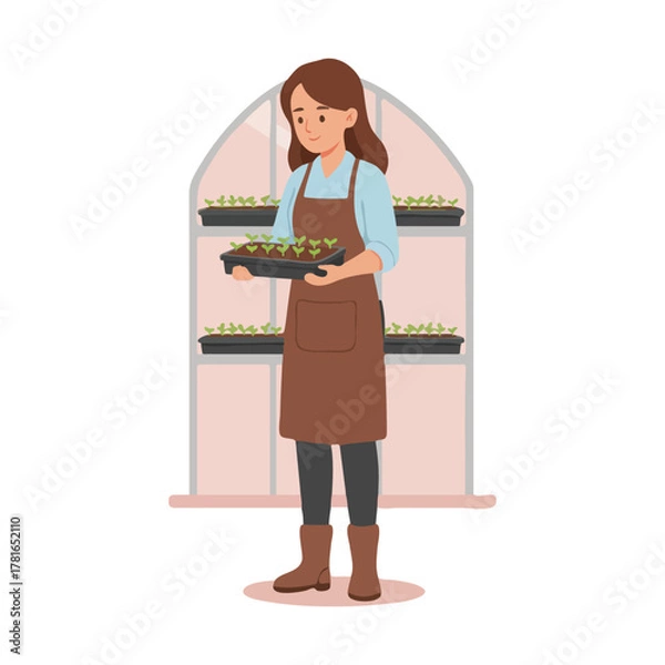 Obraz Woman holding tray of seedlings in a greenhouse.