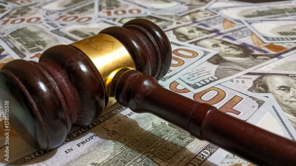 Fototapeta Wooden judge gavel placed on a pile of hundred-dollar bills representing law, justice, corruption, and financial judgment in legal or business contexts.