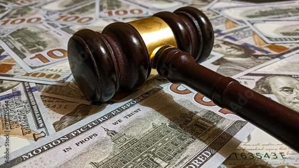 Fototapeta Wooden judge gavel placed on a pile of hundred-dollar bills representing law, justice, corruption, and financial judgment in legal or business contexts.