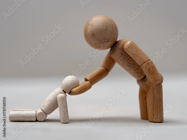 Obraz Wooden mannequin reaching hand to help fallen figure, symbolizing kindness, trust, and emotional assistance in human compassion and connection.