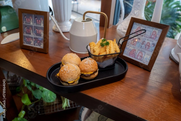 Fototapeta A delicious serving of mini burgers and fries on a wooden table. The food is arranged artfully, inviting immediate enjoyment.