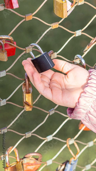 Obraz Close-up of child hand holding a padlock on the Makartsteg love lock bridge during family vacation in autumn Salzburg in Austria