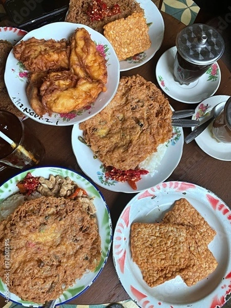 Obraz Top view of traditional Indonesian meal with crispy omelette, fried tempeh, and banana fritters served with chili and rice. Authentic local cuisine representing comfort food and culinary heritage.