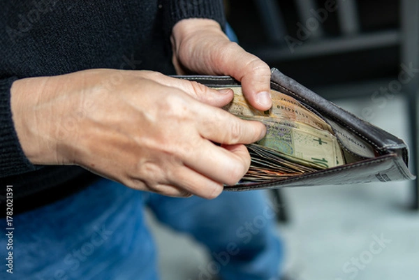 Obraz Person holding an open wallet filled with Polish banknotes. Close-up shot representing personal finance, budgeting