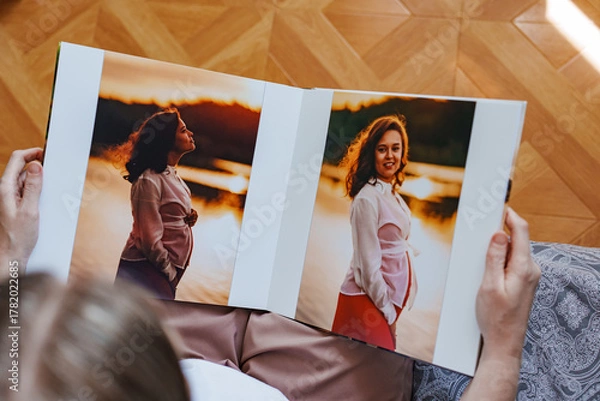 Fototapeta woman is holding and flipping through a photo book with a pregnancy photo shoot