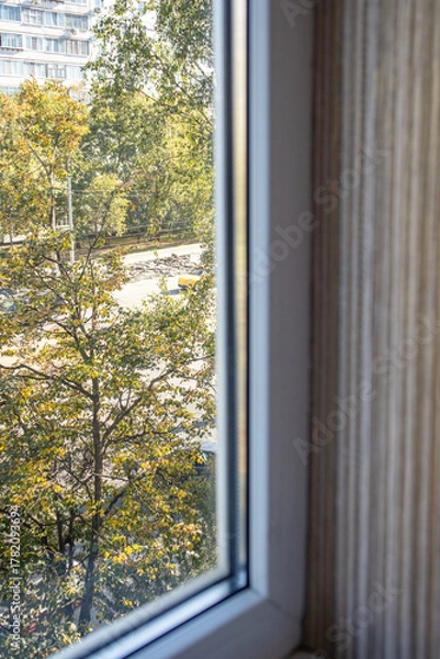 Fototapeta Window view to city street and trees vertical frame