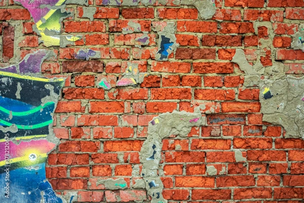 Fototapeta Abstraction of crumbling graffiti on a city street wall. Colorful abstract background. Old, cracked, peeling paint on the wall as a background.