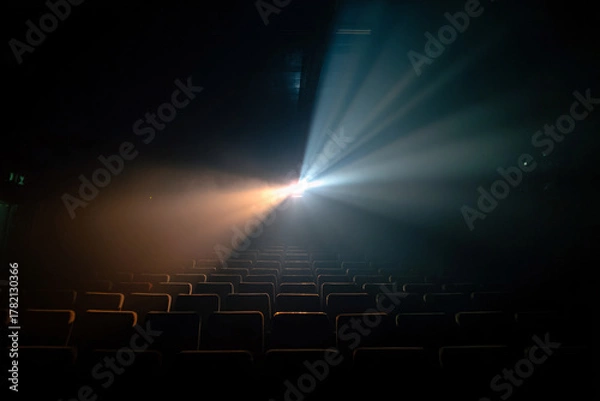 Fototapeta Dramatic theater scene with a projector light shining over empty seats.