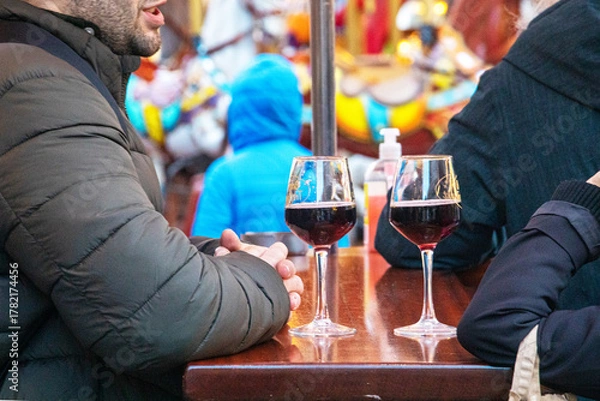 Fototapeta Drinking and socializing over glasses of punch or red wine at a table at an outdoor fair. Hugge.