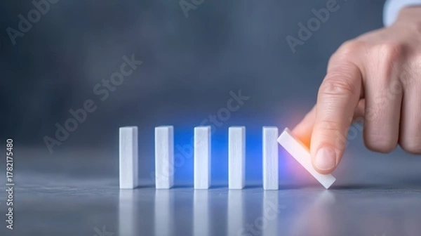 Fototapeta A Hand Starting a Domino Effect with White Rectangular Blocks on a Smooth Surface