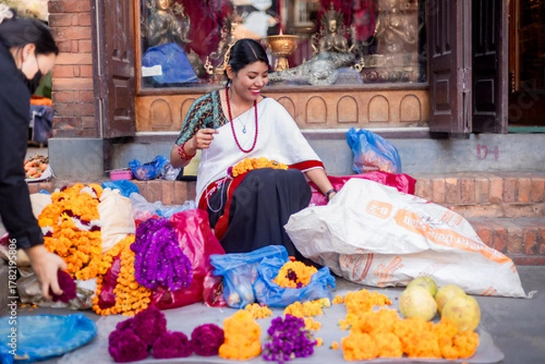 Obraz Newari Girl in traditional attire Crafting Globe Amaranth Garlands(makhmali flower) for Bhai Tika in tihar