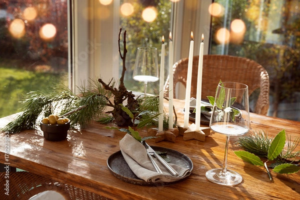 Fototapeta Atmospheric christmas table decoration in a cozy conservatory with festive bokeh lights. Decorations concept for a christmas dinner in restaurant.