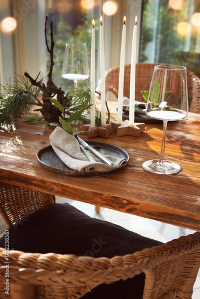 Fototapeta Atmospheric christmas table decoration in a cozy conservatory with festive bokeh lights. Decorations concept for a christmas dinner in restaurant.