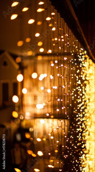Obraz Festive dark blurred background with bokeh lights, electric garland and house