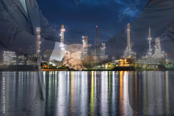 Obraz Businessmen handshaking in front of oil refinery plant. Agreement, Collaboration and  for oil and gas business concept.