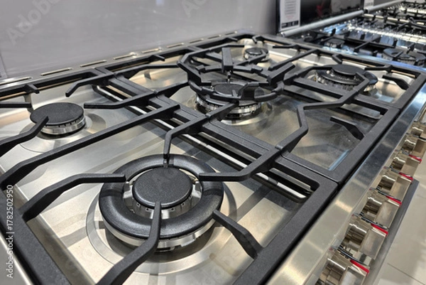 Obraz A detailed close-up of stainless steel gas stove burners with cast iron grates