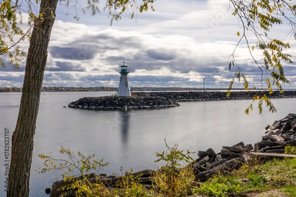 Fototapeta Serene view of Prescott Marina and lighthouse on the St. Lawrence River, capturing the tranquil ambiance of Ontario's riverside beauty.