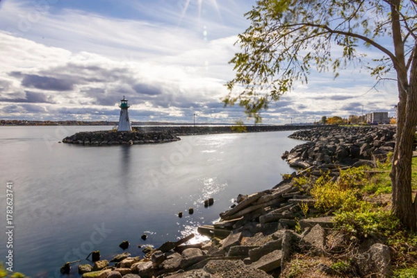 Fototapeta Serene view of Prescott Marina and lighthouse on the St. Lawrence River, capturing the tranquil ambiance of Ontario's riverside beauty.