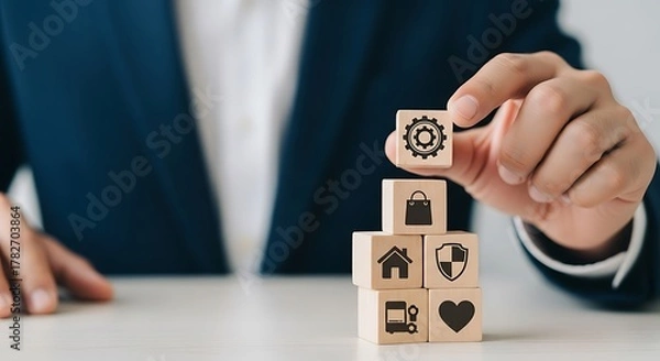 Fototapeta Businessman stacking wooden blocks with icons representing business
