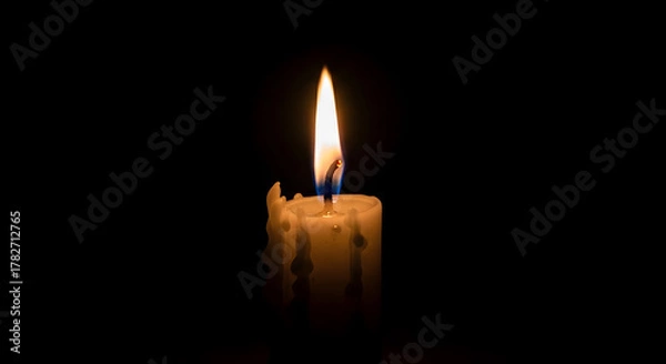 Fototapeta A single candle burning in the dark, its flame flickering gently in a soft breeze. Black background, central focus on light and shadow