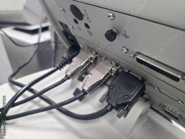 Fototapeta Connections at the back of a machine show multiple cables plugged in to power and communication ports