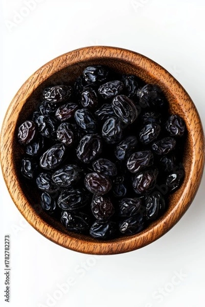 Obraz A round bowl filled with shiny dark brown raisins on a light gray background.