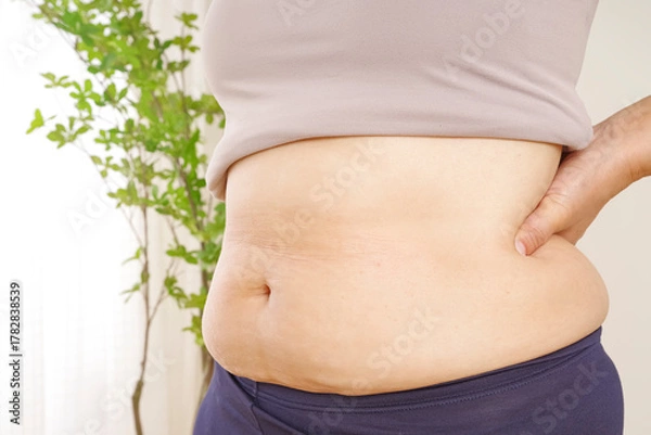 Fototapeta 中年女性のぽっこりお腹と皮下脂肪