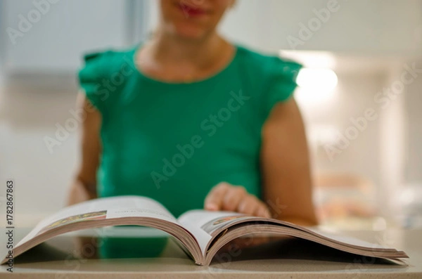 Obraz Woman reading cookbook for new kitchen recipe