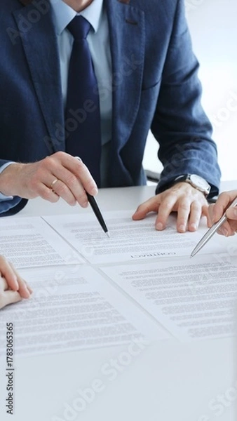 Fototapeta Business colleagues reviewing contract documents during an office meeting, discussing terms, and preparing for agreement signing, focusing on legal consultation and partnership discussion