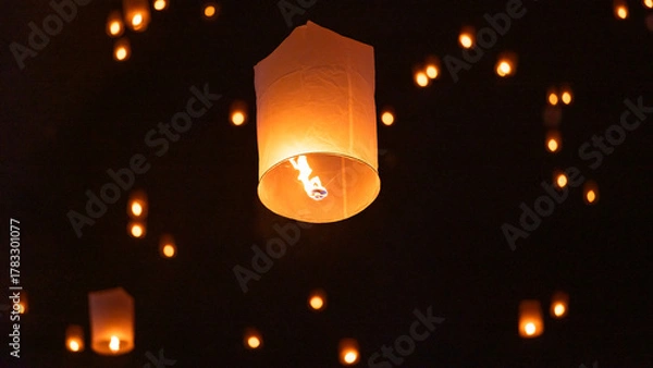 Fototapeta Sky lantern floating in the dark night sky, Tourist floating sky lanterns, Sky lanterns floating on night of Yi Peng, Loy Krathong Festival or Yi Peng Festival in Chiang Mai Thailand.