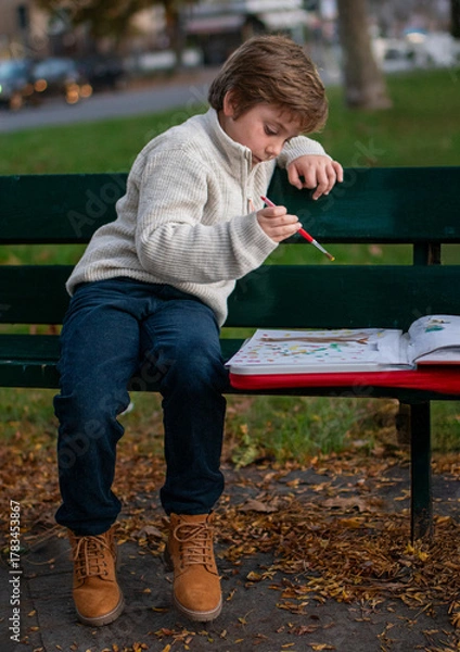 Obraz Portrait of a 7-year-old boy drawing in the park on an autumn day