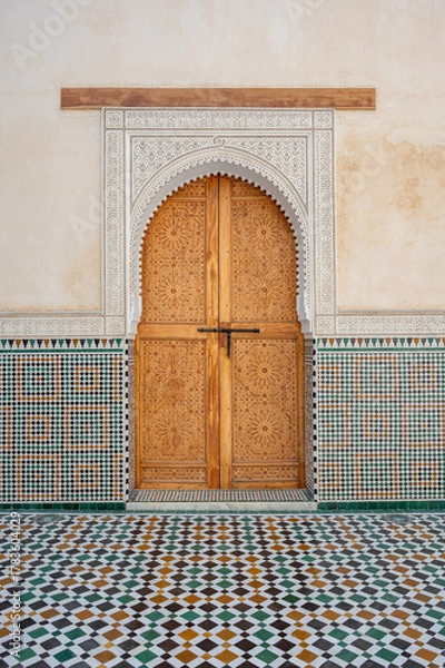 Fototapeta Highly decorated doorway framed by intricate zellige tiles and a patterned floor inside the Mausoleum of Moulay Ismail in Meknes, Morocco. The ornate craftsmanship showcases traditional Moroccan art