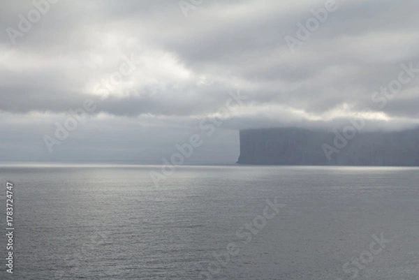 Fototapeta Misty mountain rising above the sea in the Faroe Islands, capturing the wild spirit of Nordic travel and hiking adventures.