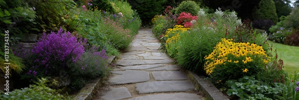 Fototapeta A charming stone pathway lined with vibrant flowers on either side, inviting viewers to take a leisurely stroll through this enchanting garden scene.