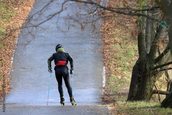 Fototapeta A roller skater walks along a track in a park