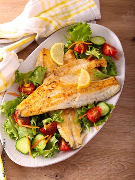 Fototapeta Fried seabass fillet with salad on plate