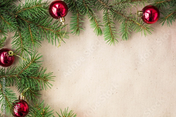 Fototapeta Fir tree branches decorated with red christmas balls as border on a rustic holiday background frame with copy space