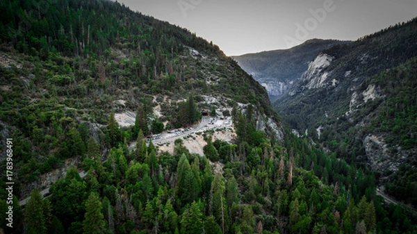 Obraz Dramatic Yosemite Valley landscape at sunrise. Golden light illuminates granite cliffs amidst lush evergreen forests. Stunning mountain vista. High resolution.