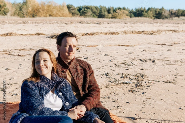 Obraz Loving couple walks on beach along sea on sunny autumn day. Weekend and lifestyle concept. High quality photo