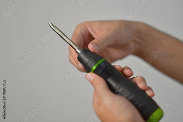 Obraz A man changing drill bit in electric screwdriver