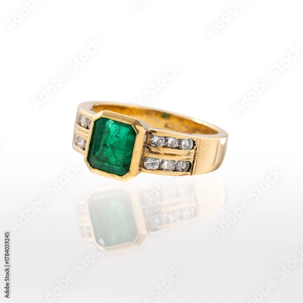 Obraz Yellow gold ring with emerald and brilliant-cut diamonds photographed on a white background with reflection