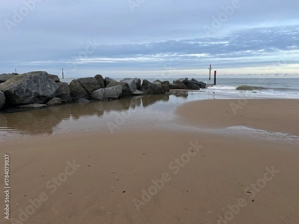 Fototapeta Beautiful natural landscape of sandy beach with vast ocean calm seas and rocky groyne barrier out to horizon in Sea Palling norfolk East Anglia UK on tranquil Winter day cold weather on holiday