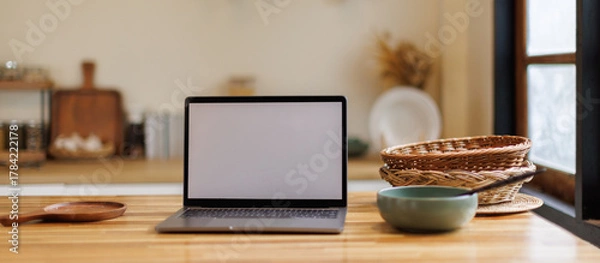 Fototapeta Open laptop with blank screen on a wooden desk in a kitchen room home office. Social media culinary concept, 
