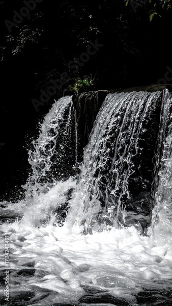 Obraz Cascading water falls over a small wall, creating a beautiful, dynamic scene