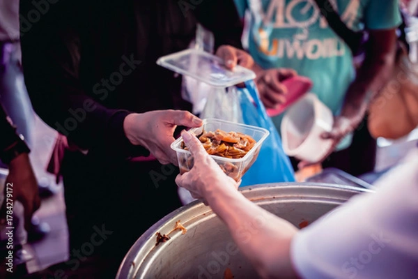 Fototapeta Volunteers are giving food to the homeless poor, Free distribution of food to the poor in today's society