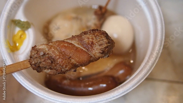 Fototapeta A steaming pot of oden with assorted ingredients like daikon, fish cakes, and skewers