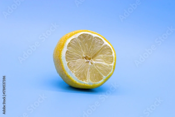 Fototapeta Half-Dried yellow lemon on a blue background, close