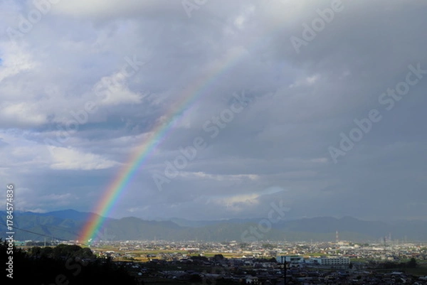 Obraz 岐阜県池田町の雨上がりの虹と光の刺す街並みと山