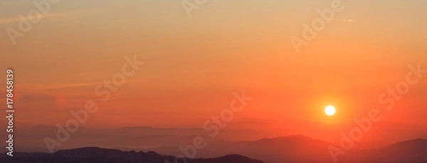 Obraz Beautiful sunset on sky over mountains background. The sun is on the right side.
